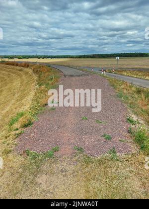 Eine kleine Straße, die in Schotter- und Schotterstraße endet. Stockfoto