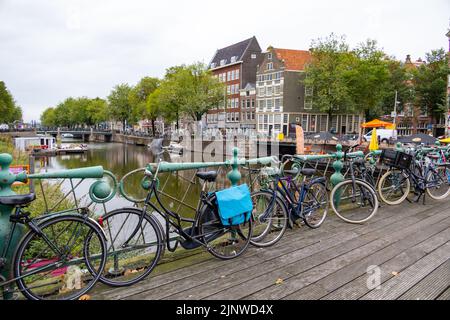 Amsterdam, Niederlande - September 30 2021: Push-Bikes auf der Grachtenbrücke geparkt mit klassischen Architekturhäusern im Hintergrund Stockfoto