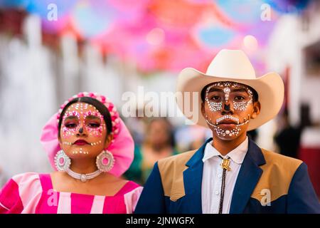 Ein junges mexikanisches Paar, beide mit Gesichtsschmuck, nimmt an den Feierlichkeiten zum Tag der Toten in Taxco de Alarcón, Guerrero, Mexiko, Teil. Stockfoto