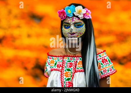 Ein mexikanisches Mädchen, das als La Catrina gekleidet ist und Gesichtssteine trägt, nimmt an den Feierlichkeiten zum Tag der Toten in Taxco de Alarcón, Mexiko, Teil. Stockfoto