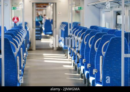 Innenraum des modernen Hochgeschwindigkeits-Expresszuges für Passagiere, Reihe leerer, weicher Sitze aus blauem Stoff. Stockfoto