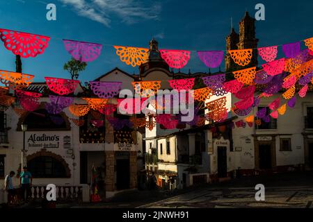 Auf dem kolonialen platz werden während der Feierlichkeiten zum Tag der Toten in Taxco de Alarcón, Guerrero, Mexiko, gepeckte Papierfahnen aufgehängt. Stockfoto