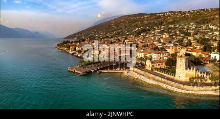 Malerische Orte des schönen Lago di Garda See. Luftaufnahme des charmanten Dorfes Torri del Benaco über Sonnenuntergang. Italien, Provinz Verona Stockfoto