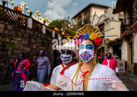 Eine junge Mexikanerin, die als La Catrina gekleidet ist und eine bestickte Gesichtsmaske trägt, tritt während der Feierlichkeiten zum Tag der Toten in Taxco, Mexiko, auf. Stockfoto