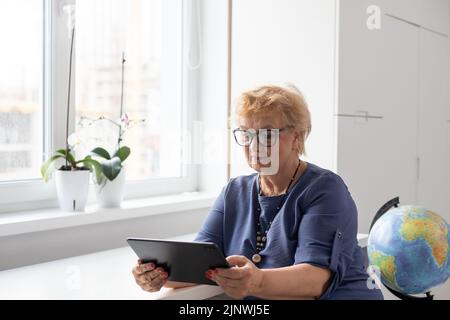 Ältere Frau, die zu Hause ein digitales Tablet verwendet. Der Einsatz von Technologie durch ältere Menschen Stockfoto