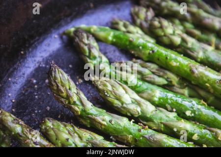 Spargel mit Zitronenschale, gegrillt im Freien in einer gusseisernen Pfanne Stockfoto