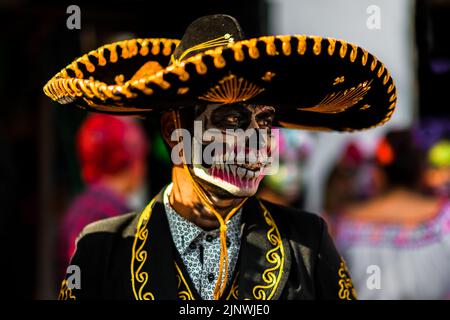 Ein mexikanischer Mann, gekleidet wie Mariachi und mit einem Gesicht als Catrin gemalt, tritt während der Feierlichkeiten zum Tag der Toten in Taxco de Alarcón, Mexiko, auf. Stockfoto