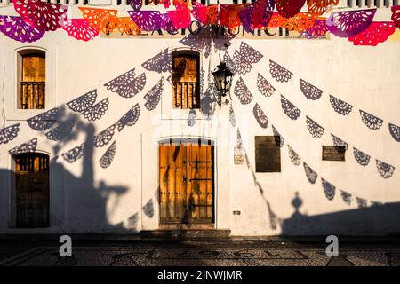 Während der Feierlichkeiten zum Tag der Toten in Taxco de Alarcón, Guerrero, Mexiko, werden auf einem kolonialen Gebäude gehängte Papierfahnen aufgehängt. Stockfoto