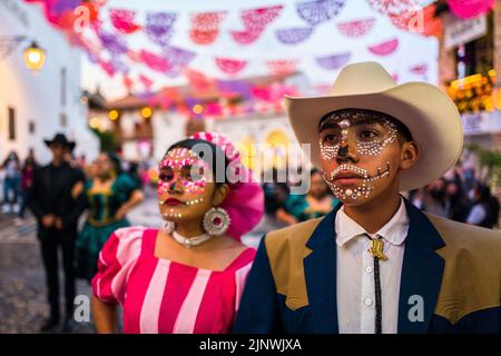 Ein junges mexikanisches Paar, beide mit Gesichtsschmuck, nimmt an den Feierlichkeiten zum Tag der Toten in Taxco de Alarcón, Guerrero, Mexiko, Teil. Stockfoto