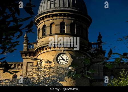 Zeitvergehen und vergangene Industriezeiten: Das Baudatum 1872 auf dem Uhrturm der ehemaligen Bliss Tweed Mill in Chipping Norton, Oxfordshire, England, Großbritannien, spiegelt sich in der ruhigen Oberfläche des kleinen Sees in Landschaftsgärten wider, die von den heutigen Bewohnern, den Pächtern von Luxuswohnungen, die nach der Schließung der Mühle im Jahr 1980 entstanden, genossen wurden. Stockfoto