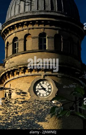 Zeitvergehen und vergangene Industriezeiten: Das Baudatum 1872 auf dem Uhrturm der ehemaligen Bliss Tweed Mill in Chipping Norton, Oxfordshire, England, Großbritannien, spiegelt sich in der ruhigen Oberfläche des kleinen Sees in Landschaftsgärten wider, die von den heutigen Bewohnern, den Pächtern von Luxuswohnungen, die nach der Schließung der Mühle im Jahr 1980 entstanden, genossen wurden. Stockfoto