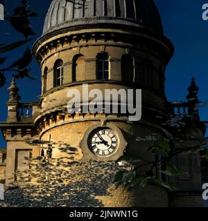 Die Zeit vergeht und die Industriezeit vergeht: Das Baudatum 1872 auf dem Uhrenturm der ehemaligen Bliss Tweed Mill in Chipping Norton, Oxfordshire, England, Großbritannien, spiegelt sich in diesem quadratischen Format in der ruhigen Oberfläche des Sees in den Landschaftsgärten wider, die von den heutigen Bewohnern genossen werden. Die Pächter von Luxuswohnungen, die nach der Schließung der Mühle im Jahr 1980 entstanden sind. Stockfoto