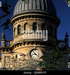 Eine sanft fokussierte, quadratische Ansicht des industriellen Erbes Großbritanniens: Der Uhrturm der ehemaligen Bliss Tweed Mill in Chipping Norton, Oxfordshire, England, Großbritannien, spiegelt sich in der ruhigen Oberfläche des Sees in den Gartenanlagen wider, die von den heutigen Bewohnern, den Pächtern von Luxuswohnungen, die nach der Schließung der Mühle im Jahr 1980 geschaffen wurden, genossen werden. Stockfoto