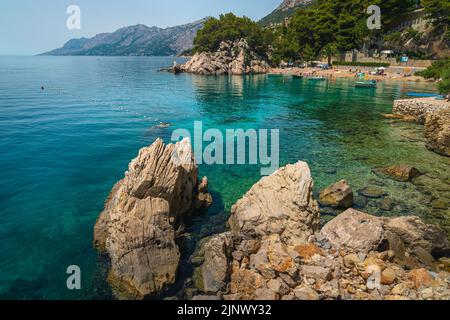 Erstaunlicher Strand und felsige Küste mit verankerten Booten, Brela, Dalmatien, Kroatien, Europa Stockfoto
