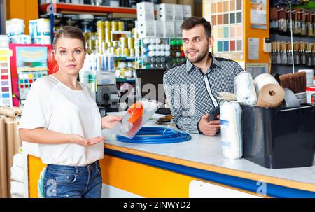 Junge Verkäuferin, die mit verärgerten weiblichen Kunden im Werkzeugwarenladen diskutiert Stockfoto