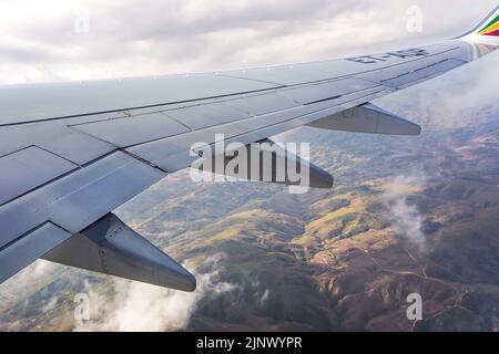 Addis Abeba, Äthiopien - 07. Mai 2019: Blick aus dem Passagierfenster der äthiopischen Fluggesellschaften Boeing 737, Verkehrsflugzeug, Wolken und kleiner Hügel sichtbar Stockfoto