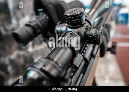 Schwarze Schießskop-Optik auf Gewehr montiert, die auf der Waffenmesse ausgestellt ist, Detailansicht der Einstellknöpfe Stockfoto