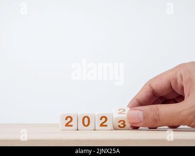 Nahaufnahme Hand Umblättern der 2022 bis 2023-Jahres-Zahlen Kalender auf weißen Würfel Blöcke für die Vorbereitung der neuen Jahr ändern, beginnen und starten Sie neue Geschäfte t Stockfoto