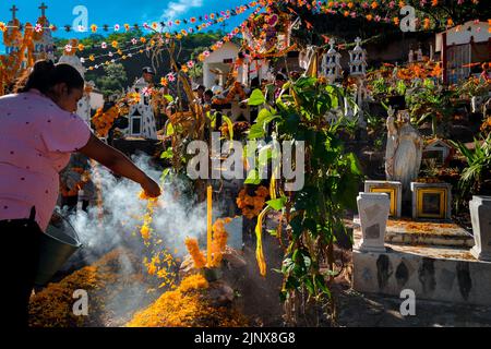 Eine indigene Frau aus Mixteken schmückt während der Feierlichkeiten zum Tag der Toten in Xalpatláhuac, Guerrero, Mexiko, ein Grab auf einem Friedhof. Stockfoto