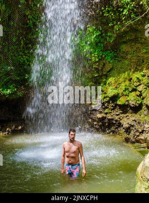 Junge Männer entspannen sich am Toraille Wasserfall St. Lucia. St. Lucia Dschungel Wasserfall und Männer schwimmen. Toraille Falls Sain Lucia Stockfoto