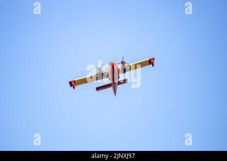 Canadair-Flug, Feuerwehrflugzeug, Scooper-Flug auf blauem Himmel im Hintergrund, unter Sicht. Gelbrote Farbe Wasserflugzeug für Rettung und Transport. Stockfoto