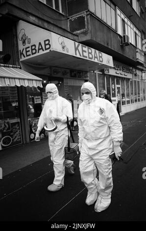 Zwei medizinische Fachkräfte betreuen einen COVID-Patienten in Bukarest vor einem Kebab-Shop Stockfoto