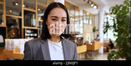 Lächelnde junge asiatische professionelle Frau trägt Anzug, Porträt, Banner Stockfoto
