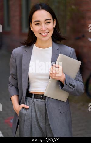 Junge stilvolle asiatische Geschäftsfrau Führer hält Tablet, Outdoor-Porträt. Stockfoto