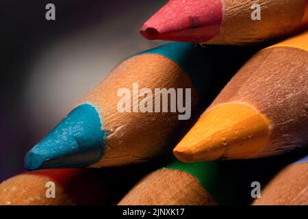Extreme Nahaufnahme von spitzen blauen, rosa, gelben und grünen Buntstiften, Schul- und Kunstbedarf Stockfoto