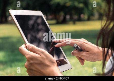 Nahaufnahme einer Frau, die in einem Park schreibt und ein Notizbuch benutzt Stockfoto