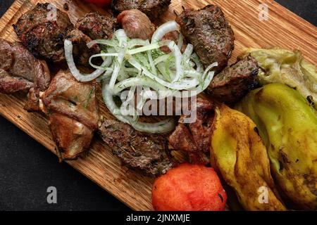 Verschiedene Grillgerichte, Kebabs, Rippchen auf einem Holzbrett mit gebratenem Gemüse Stockfoto