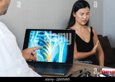 Arzt, der eine Röntgenaufnahme von Schmerzen in den Rippen einer Patientin zeigt Stockfoto