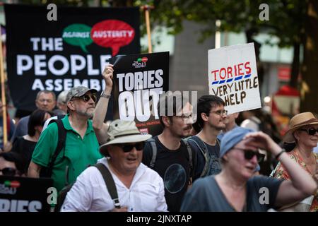 Manchester, Großbritannien. 14. August 2022. Menschen mit Plakaten gehen auf die Straße zum Peterloo-marsch für Demokratie. Gewerkschaften und lokale Gemeinschaften kommen zusammen, um der Regierung zu zeigen, dass die Lebenshaltungskosten außer Kontrolle geraten sind und dass die Menschen sich zusammenschließen werden, um zurückzukämpfen. Kredit: Andy Barton/Alamy Live Nachrichten Stockfoto