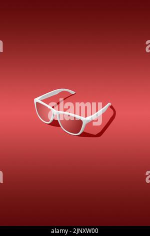Rote Sonnenbrille mit rotem Hintergrund. Studioaufnahme. Stockfoto