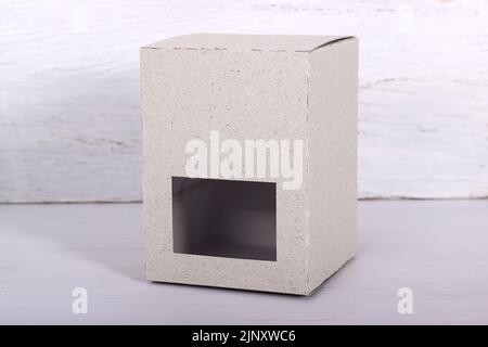 Helle Kartonverpackung mit Fenster vor hellem Holz Stockfoto
