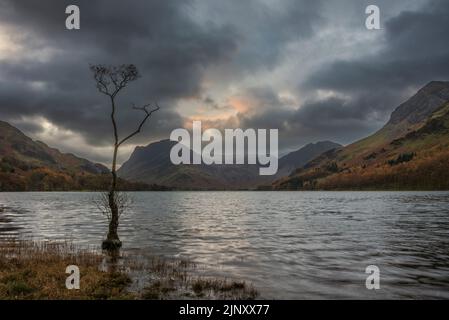 Atemberaubendes Landschaftsbild von Buttermere im Lake District bei Sonnenaufgang im Herbst mit dramatischem stürmischen Himmel Stockfoto