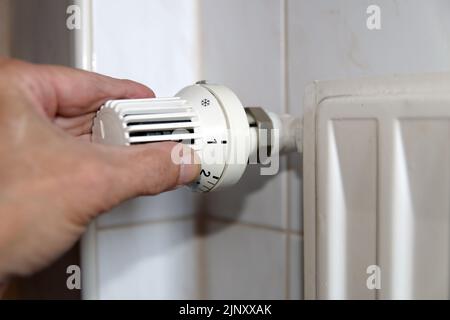 Gasknappheit und steigende Heizkosten: Hand an Heizkörperthermostat Stockfoto