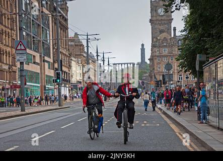 Princes Street, Edinburgh, Schottland, Großbritannien. EdFringe Straßenkünstler, Todd Various auf seinem adaptierten Penny Farthing-Fahrrad und Mat Keys auf seinem Rennrad haben ein ungeplantes, lustiges Rennen entlang der Princes Street, viel zur Belustigung der Passanten. Quelle: Arch White/alamy Live News. Stockfoto