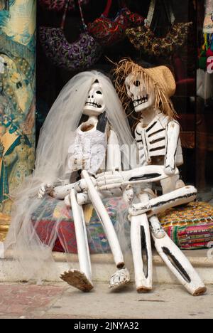 Eine mexikanische Skelett-Hochzeit zu Halloween, die Frau trägt einen Brautschleier und der Mann einen Strohhut. Stockfoto