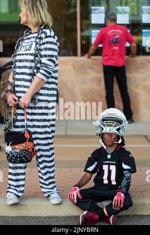 Mutter im gestreiften Frauengefängnis Kostüm und Sohn im Fußballkostüm auf der Fountain Hills Halloween Party in Arizona, USA Stockfoto