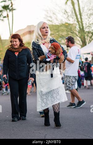 Blonde Frau mit einem braunen Pudel und einem Hundekostüm für tödliche Puppen auf einer Halloween-Party in Fountain Hills, Arizona, USA. Stockfoto