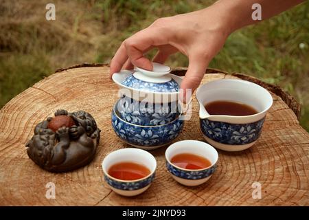 Bereiten Sie chinesischen schwarzen Tee im Teeset auf dem Holztisch zu. Trinken Sie Tee in der Natur. Stockfoto