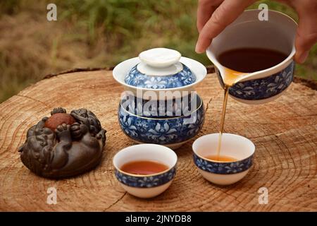 Bereiten Sie chinesischen schwarzen Tee im Teeset auf dem Holztisch zu. Trinken Sie Tee in der Natur. Stockfoto