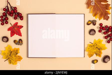 Open-Copy-Raumbuch, umgeben von Herbstdekorationen auf beigem Hintergrund. Flach liegend Stockfoto