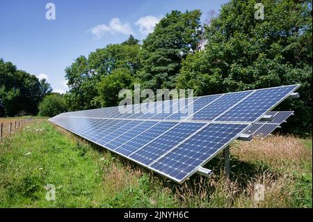 Eine Reihe von Solarmodulen, die auf einem ländlichen Gebiet im Vereinigten Königreich installiert sind Stockfoto