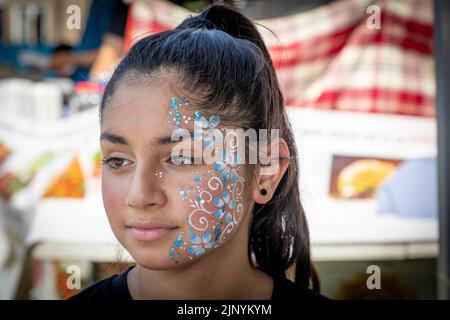 Sonntag, 14. August 2022 - Palmyra Square, Warrington, Ceshire, England, Großbritannien - nach einer zweijährigen Wartezeit aufgrund der COVID-Pandemie und unter brennender Sonne veranstaltete die Warrington Ethnic Communities Association (WECA) ihr jährliches MELA-Festival, das den Zusammenhalt der Gemeinschaft erfolgreich fördert und die Integration unterstützt. Die Veranstaltung begann im Rathaus von Warrington mit einem Spaziergang durch die Stadt zum Palmyra Square. Die Leute nutzten die Gelegenheit, um sich ein Henna Tattoo zu holen. Quelle: John Hopkins/Alamy Live News Stockfoto