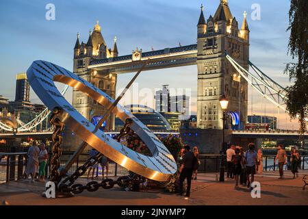 London, England - 2022. Juni, Zeitmesser Sonnenuhr, von Wendy Taylor, am St Katharine Dock und der Tower Bridge über der Themse in London, bei Dämmerung. Stockfoto