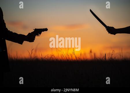 Katana gegen Revolver kämpfen im Feld. Militärischer Konflikt in Asien. Schlacht der großen Länder. USA, Taiwan gegen China im Konzept des politischen Weltkriegs Stockfoto