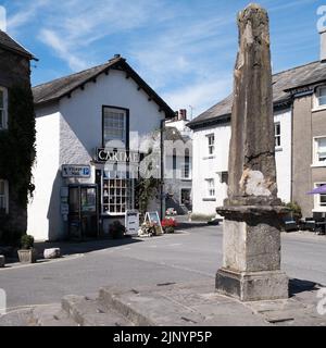 Auf den Fischsteinen auf dem Devonshire Square Cartmel, Cumbria, England, steht ein antiker Steinobelisk Stockfoto