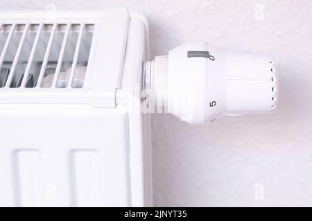 Der Temperaturregler des Heizkörpers der Wasserheizung im Wohnzimmer. Nahaufnahme. Weiße Heizbatterie. Stockfoto